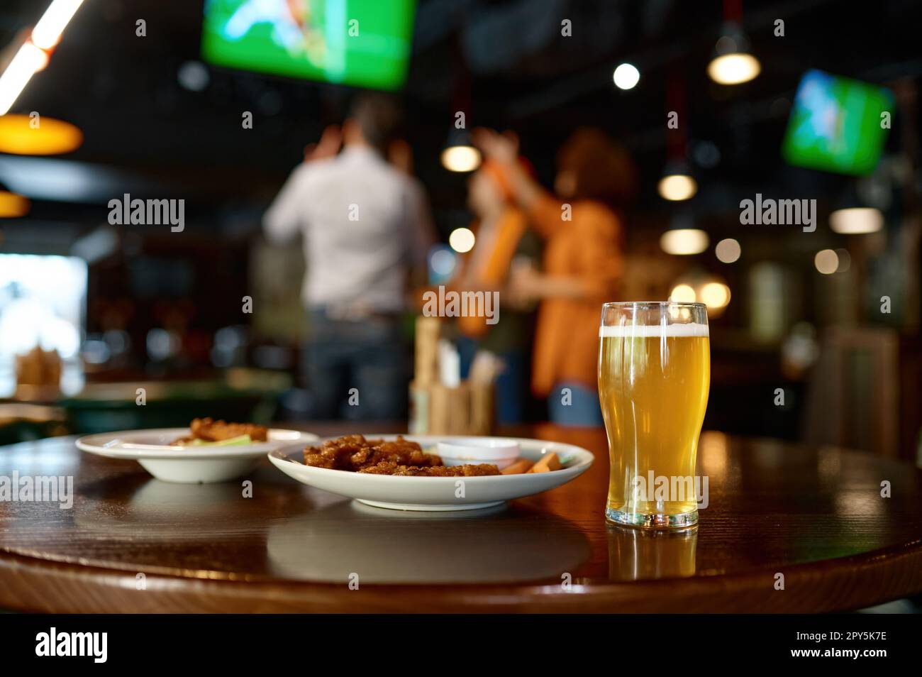 Beer glass and fast food snack on table in sports bar Stock Photo