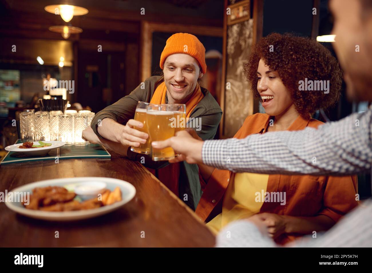 Happy friends drinking beer while rest sitting at bar counter desk Stock Photo