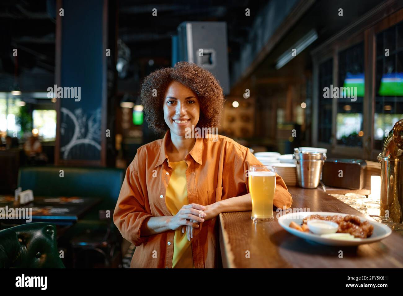Portrait of smiling pretty woman at sports bar counter desk Stock Photo