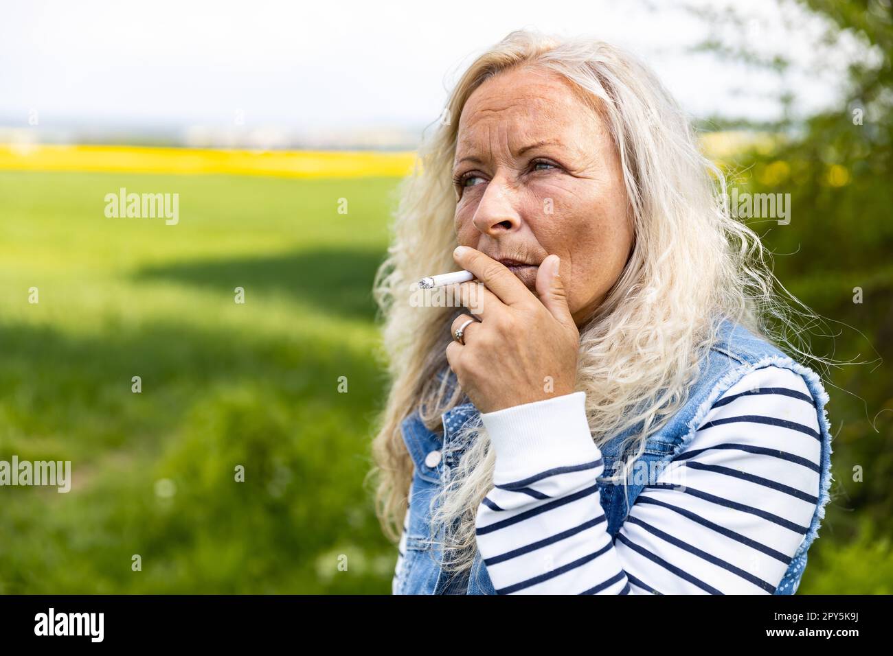 Portrait from a Lady smoking outdoor a cigarette. Stock Photo