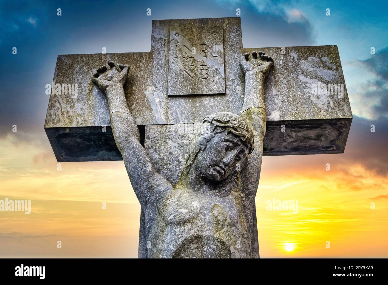 Jesus on the cross with dramatic sunset as background Stock Photo