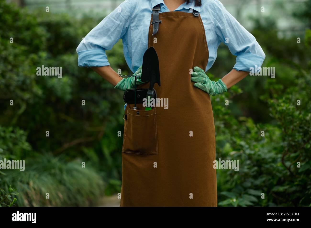 Closeup female gardener in overalls with garden tool in pocket Stock Photo