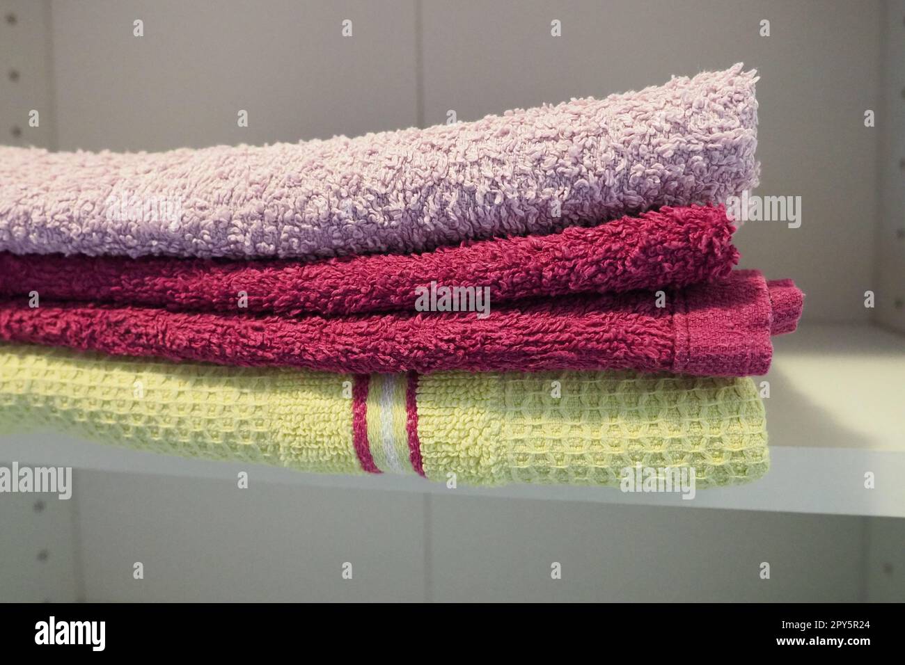 Towels on a shelf in a white Clean ironed pink and yellow