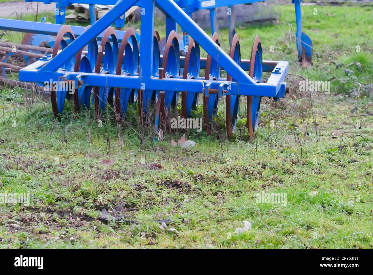 Blue heavy agricultural equipment like plow with sharp steel discs for
