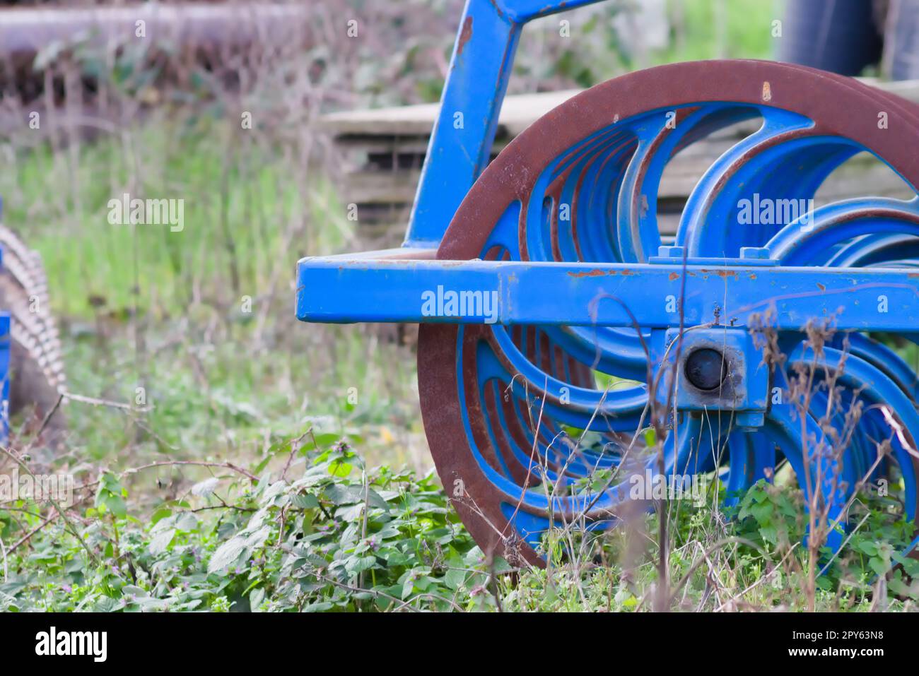 Blue heavy agricultural equipment like plow with sharp steel discs for