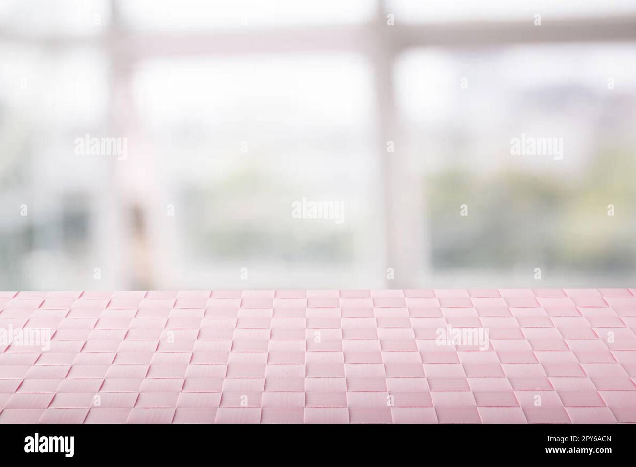 Empty table product. Closeup of a empty pink tablecloth or napkin on table over abstract blurred bright windows background. Template for your food and product display montage. Stock Photo