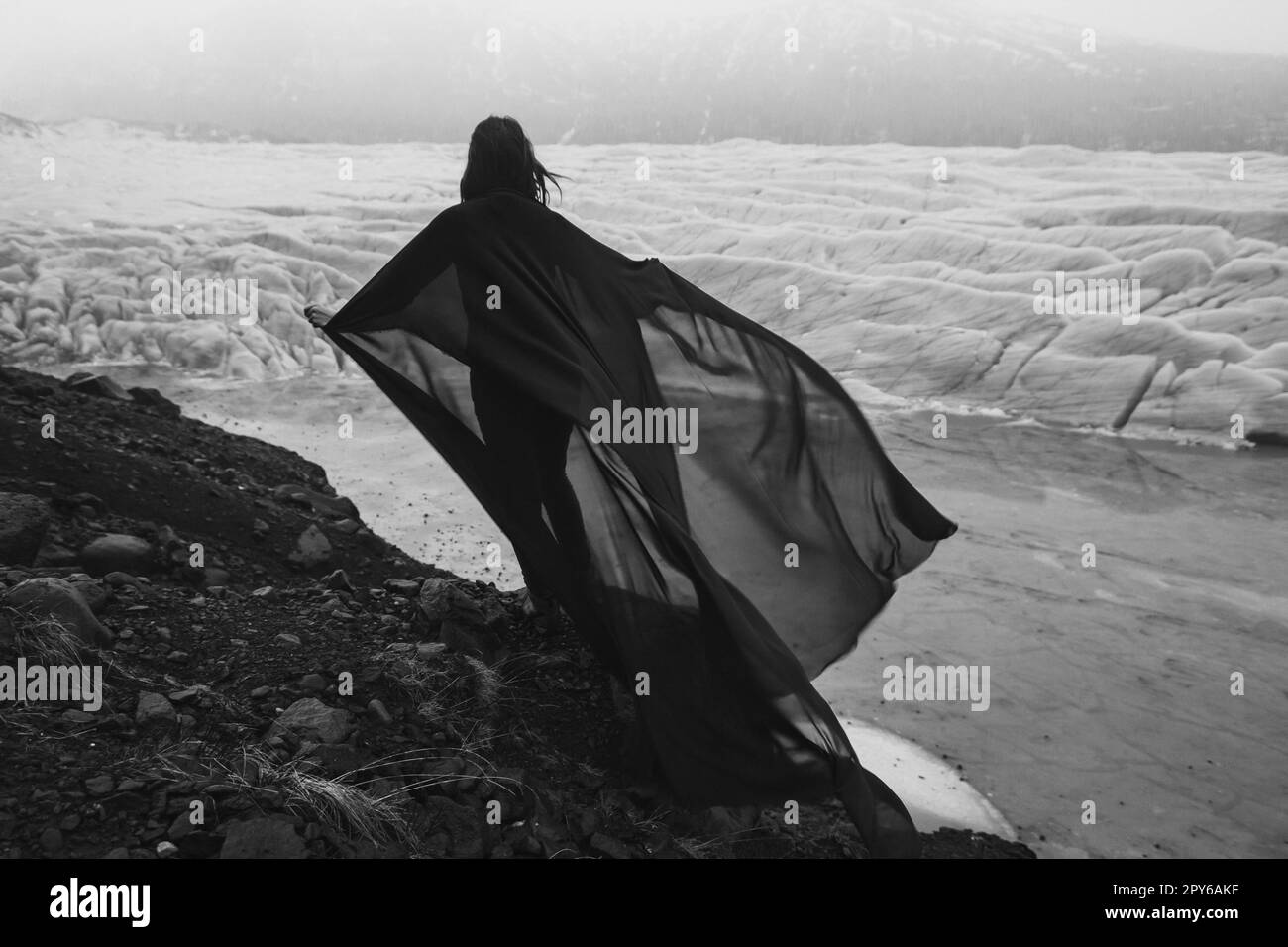 Woman holding waving chiffon fabric on rock monochrome scenic photography Stock Photo