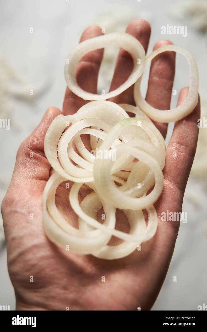 Ring sliced onions on mans hand. Photo show how does onion sliced into