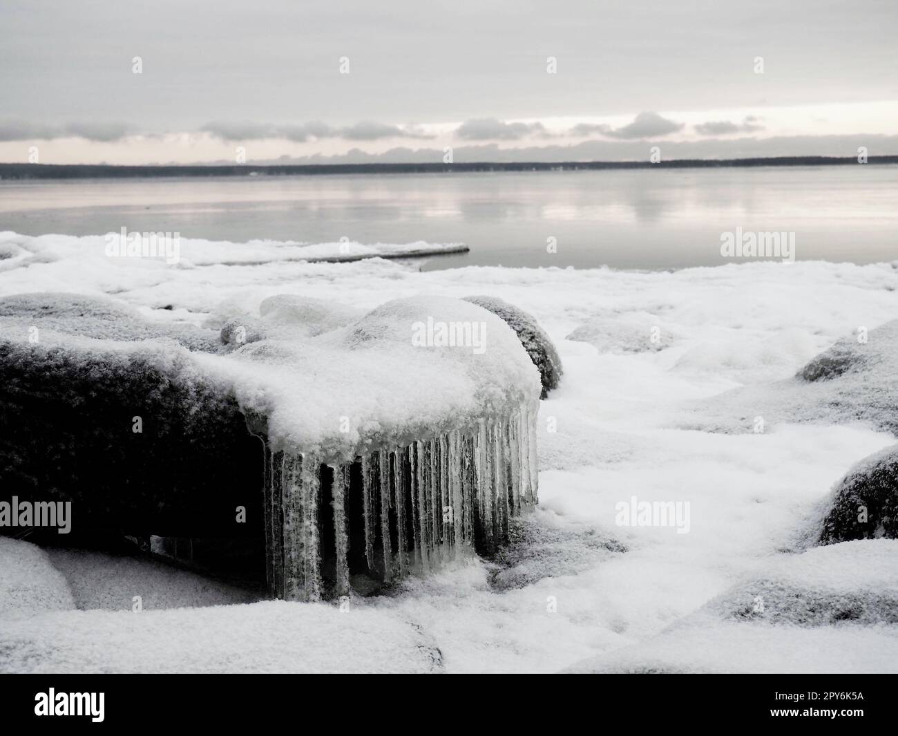 Ice icicles hanging down. Northern arctic winter season. Frozen nature. Retro or vintage style. Black and white image. Frozen water on the lake. Karelia, Russia, December 2020. Lake Onega Stock Photo
