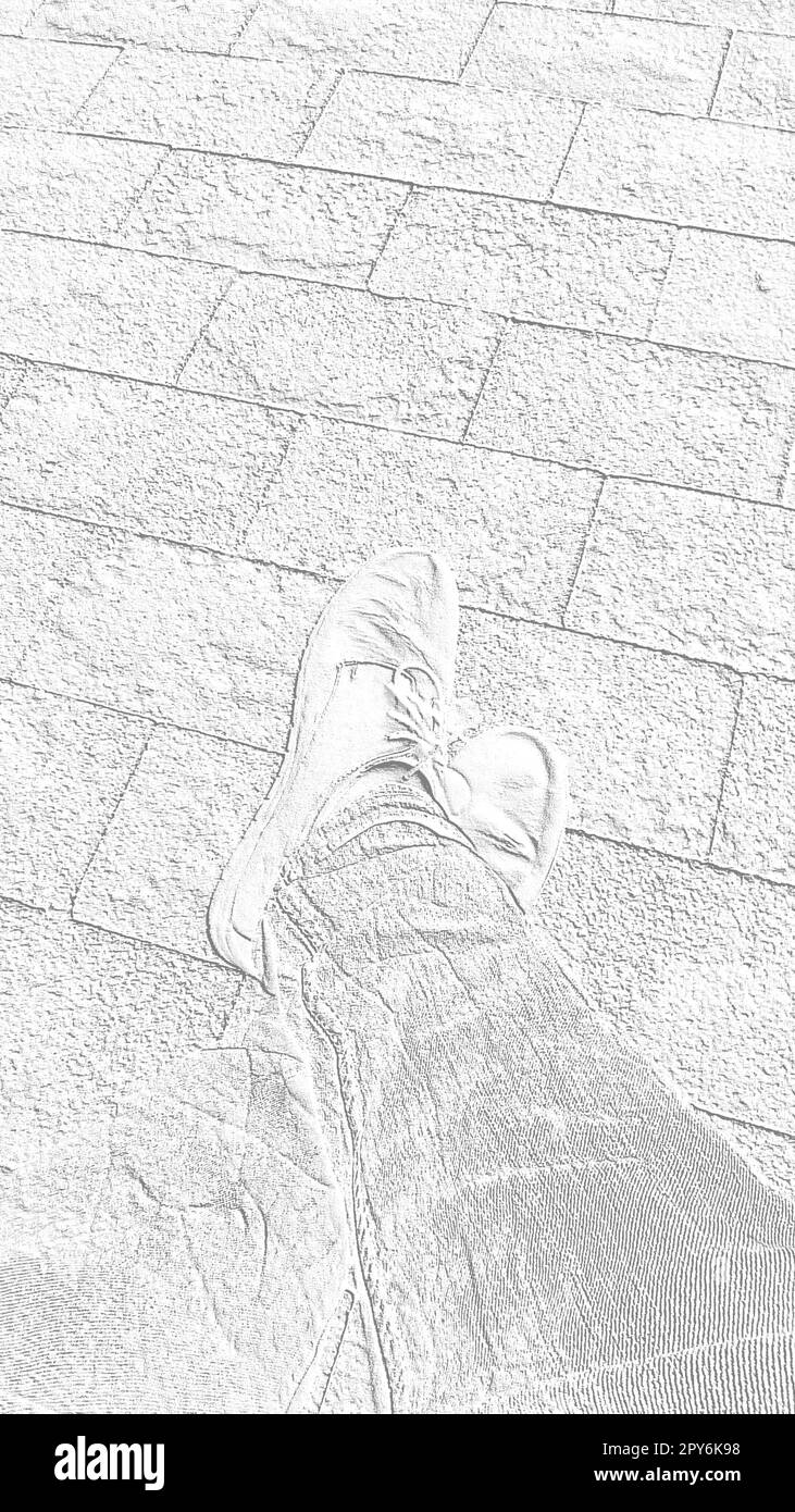 Feet in boots against the background of street tiles or the road. Two seated legs crossed, photographed from above while sitting. Monochrome white and gray image. Vertical image Stock Photo