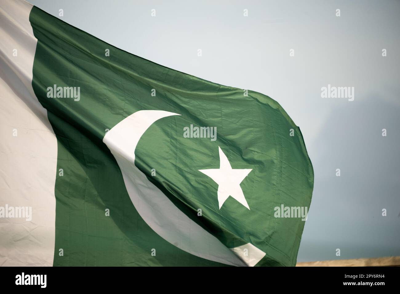 The national flag of Pakistan flying in the blue sky with clouds Stock Photo