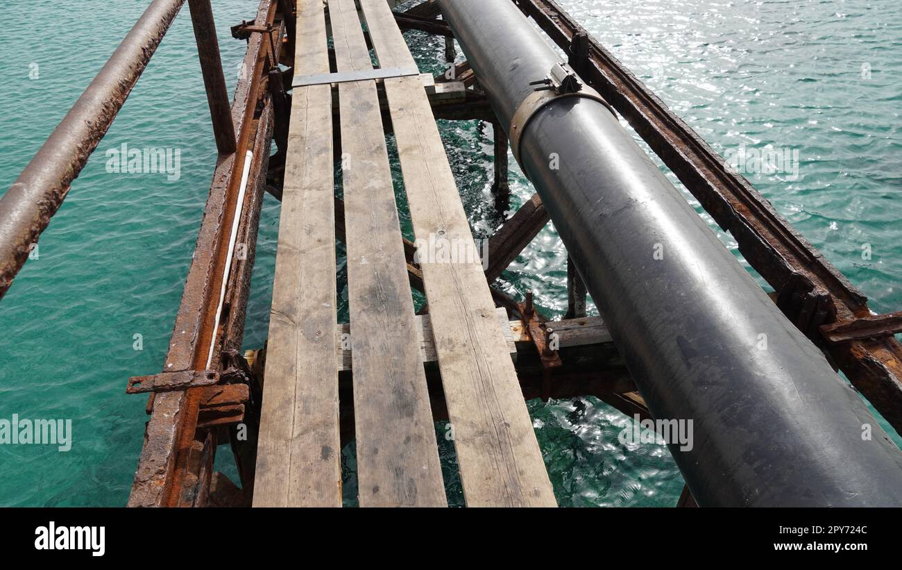 View of old deck,  by the Mediterranean Sea, Israel .Remains of a rusted handrails on a waterfront. Metal corrosion due to frequent exposure to sea water close-up Stock Photo