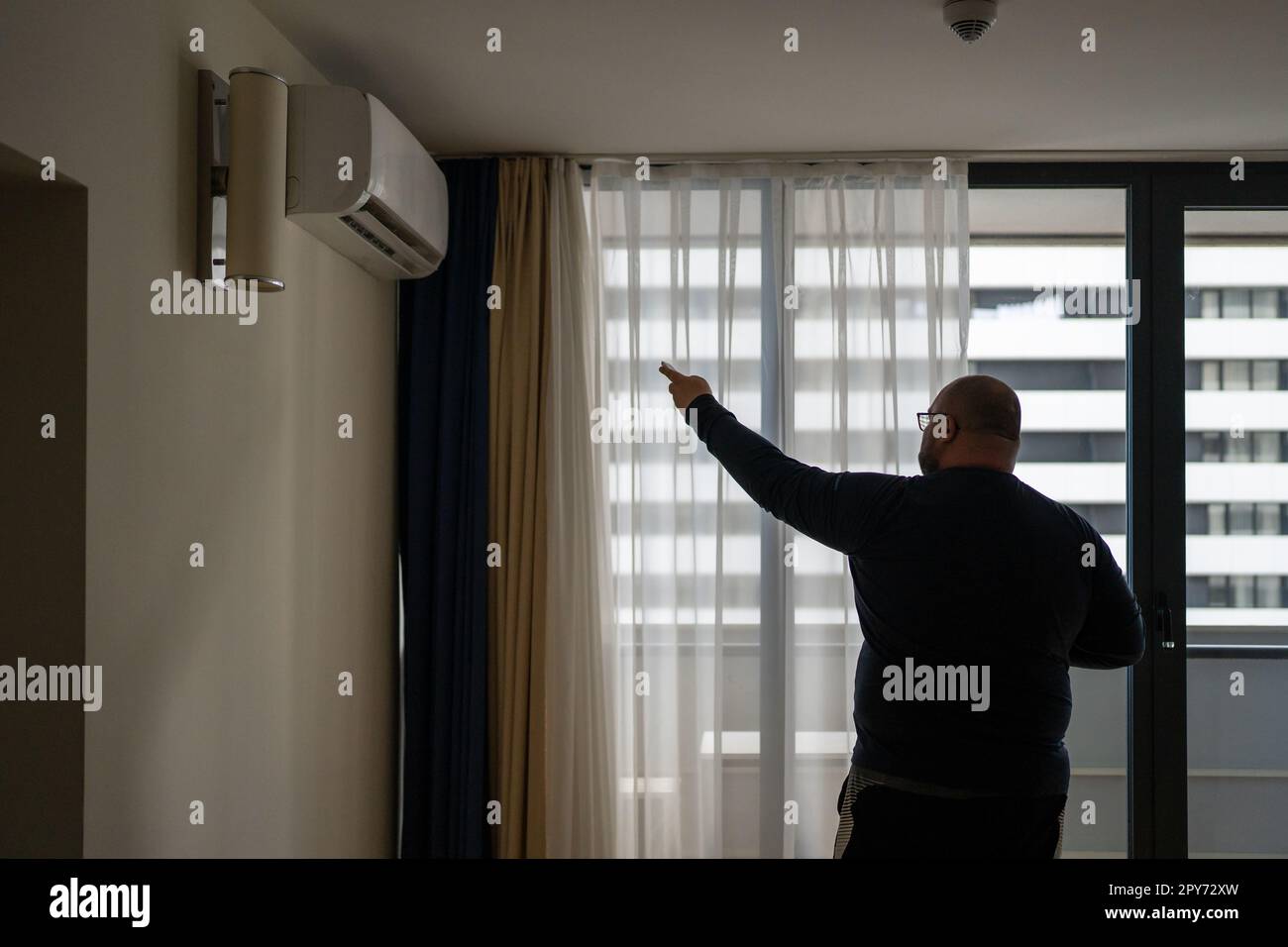Overweight man switches on air conditioner at home in summer feels