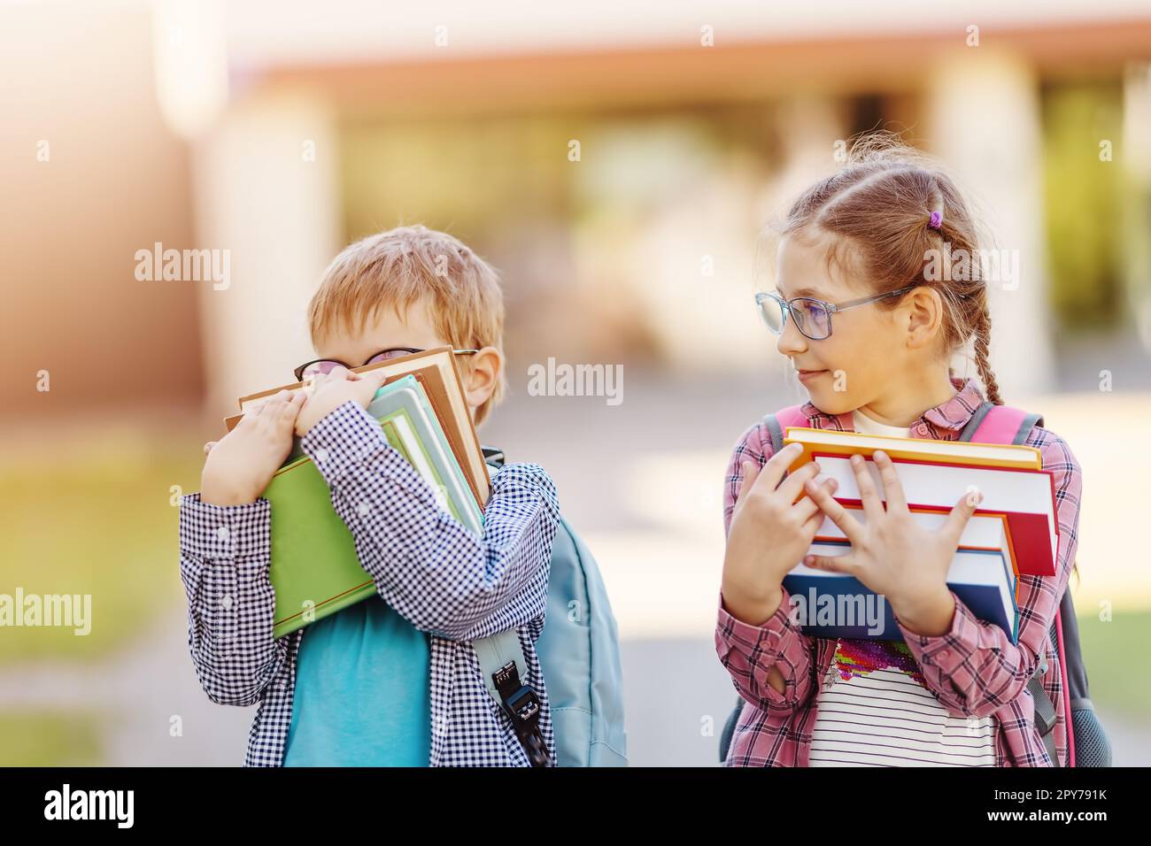Girl and boy in glasses standing with books in their hands. Stock Photo