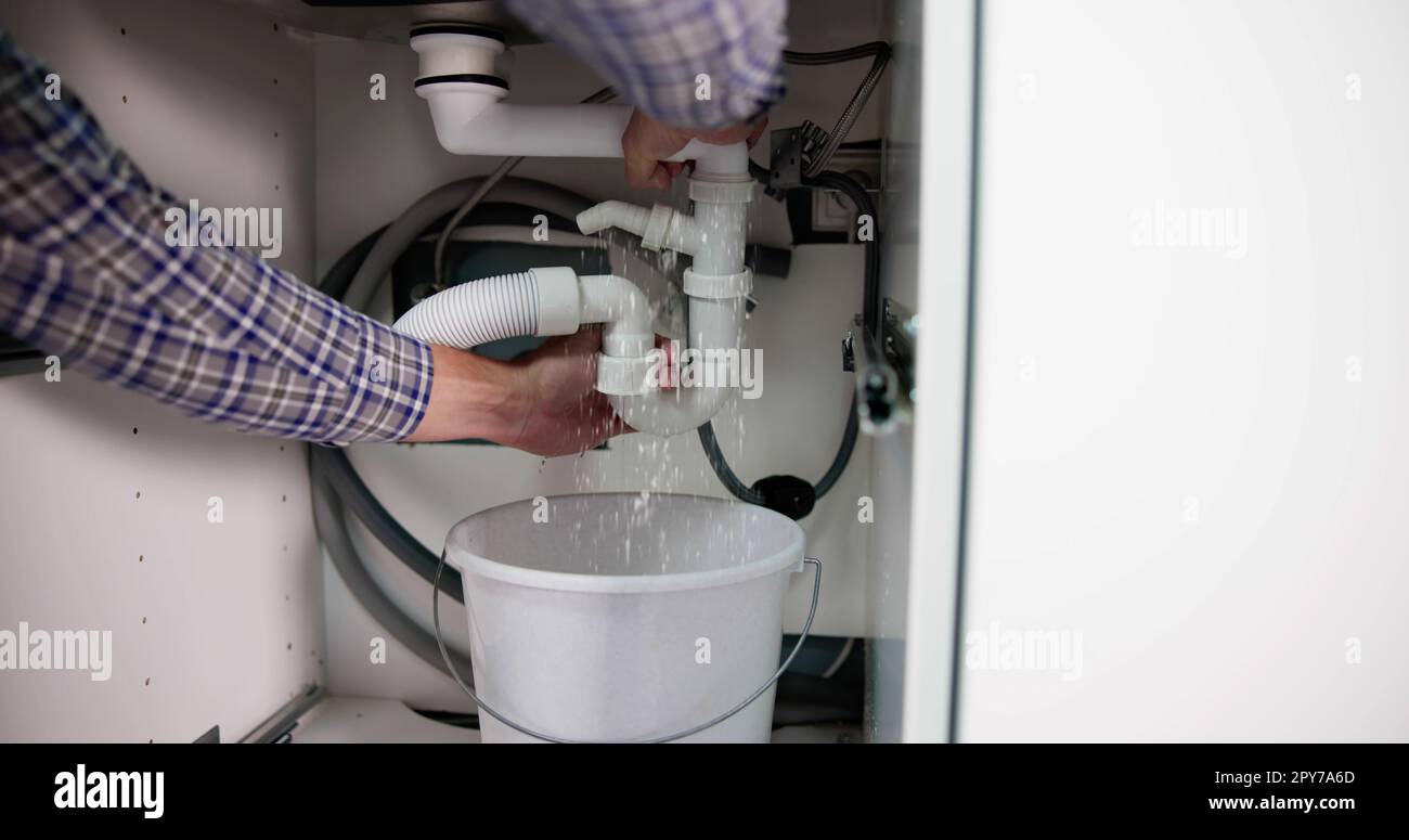 Plumber Fixing Pipe Leak Stock Photo