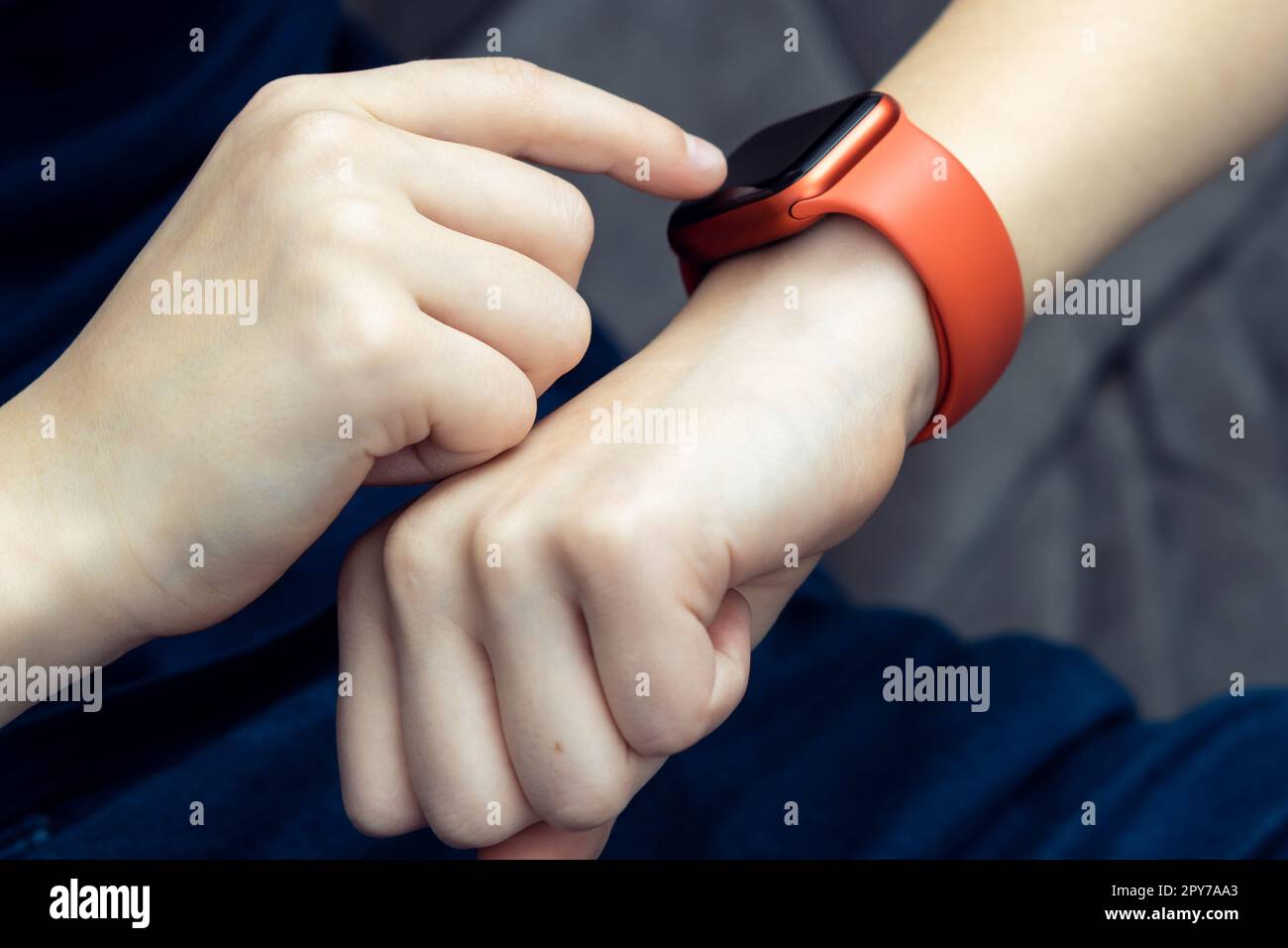 Unrecognizable teenager male hand typing on red smart watch on hand, wrist watch technology. Call and health application Stock Photo