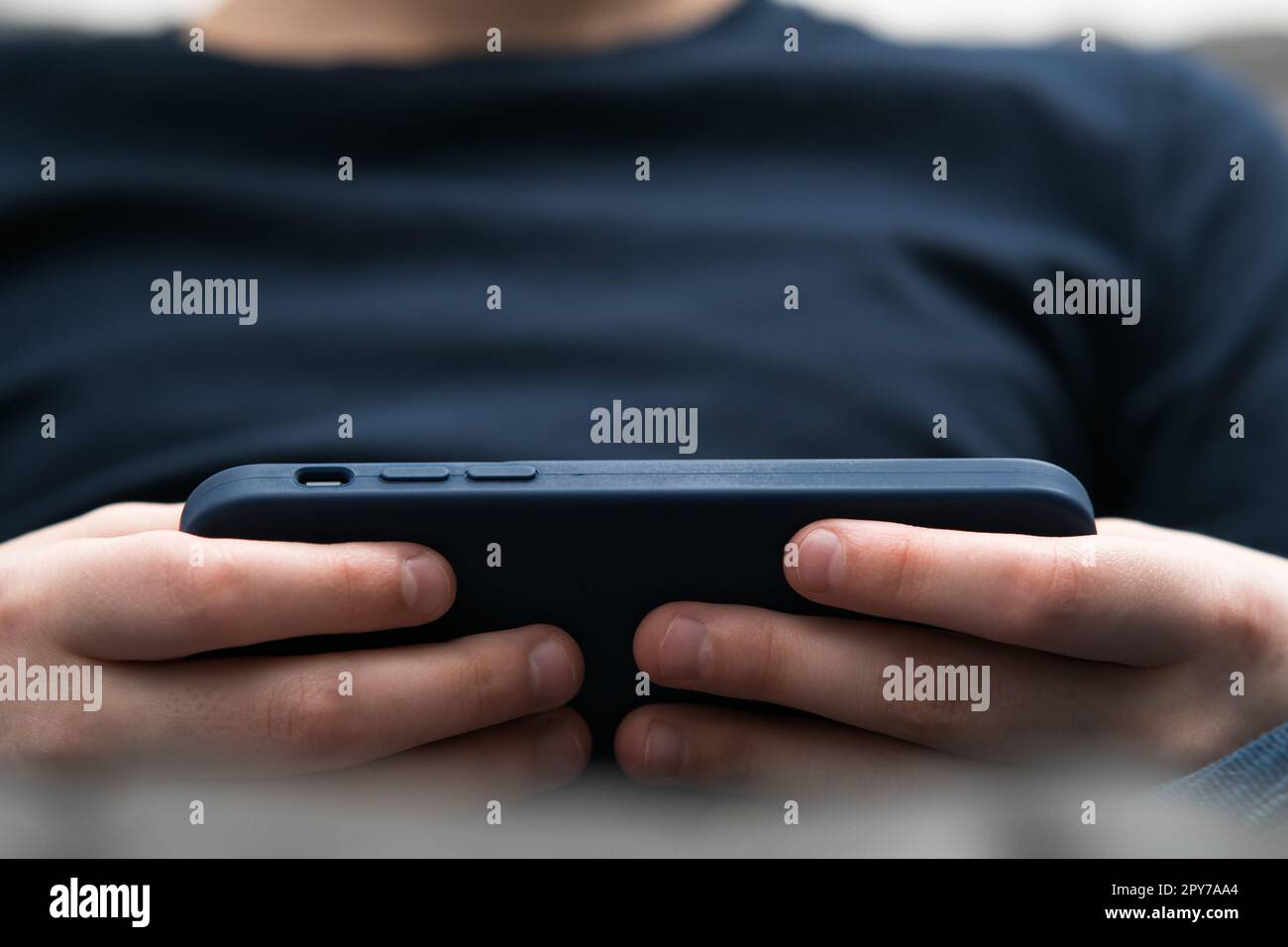 Close up blurred boy hands with smartphone in cover in horizontal orientation. Watching movies and surfing internet Stock Photo