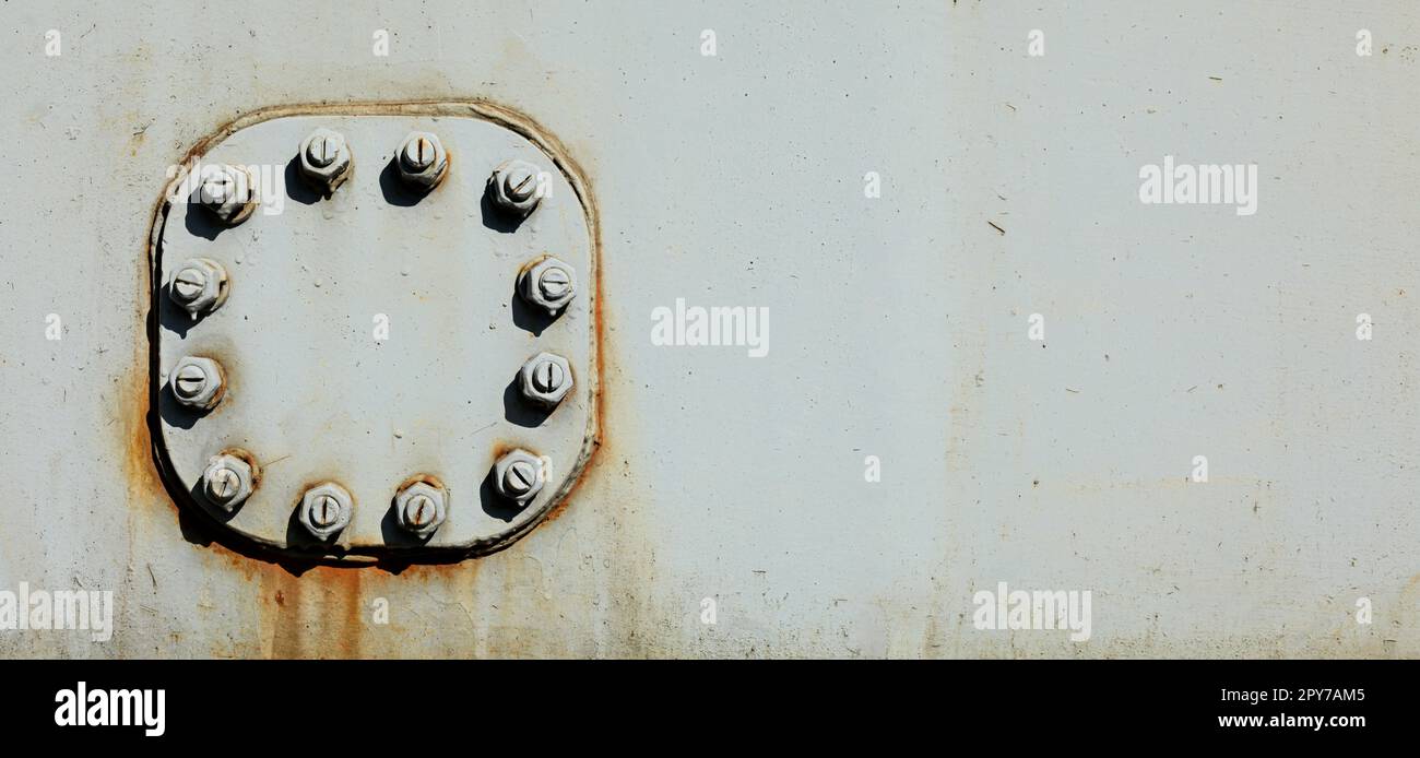 Large nuts and bolts on gray steel plate of rail bridge, lit by bright sun. Abstract industrial background, space for text on the right. Stock Photo