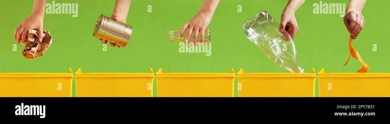 Child's hands throw paper, metal, glass, plastic, organic garbage into different yellow containers on green background Stock Photo