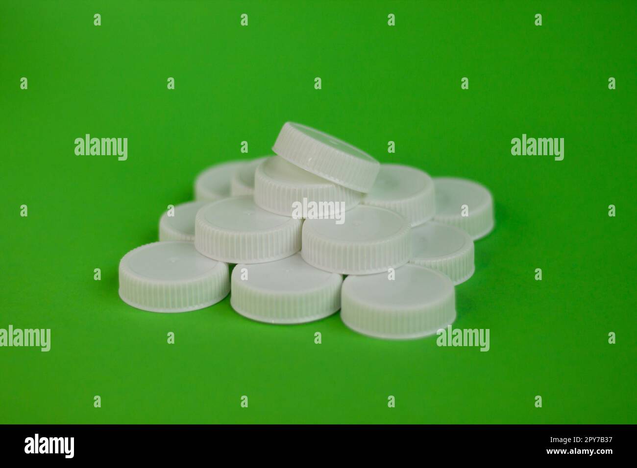 Pyramid of white plastic bottle caps on a green background