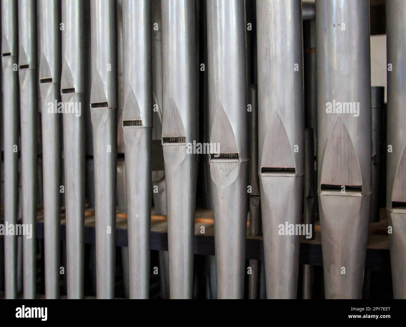 Many organ pipes stand side by side in an organ over a bellows Stock