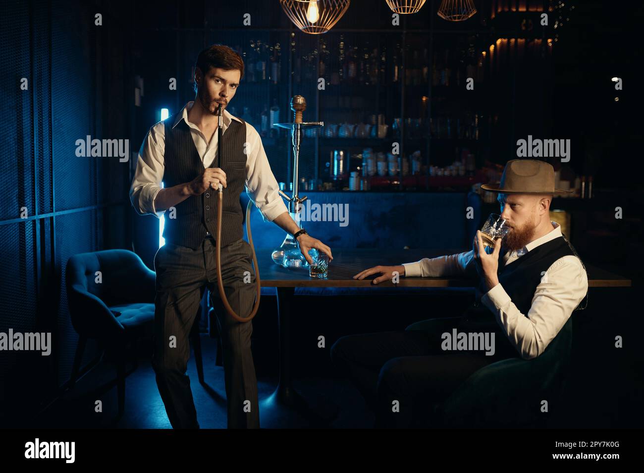 Serious guys smoking hookah while rest in the pub Stock Photo