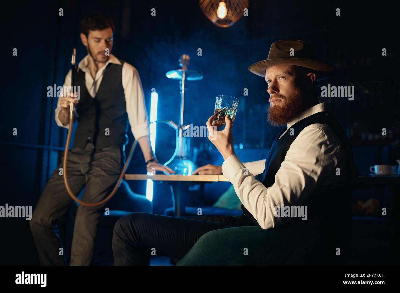 Serious guys smoking hookah while rest in pub Stock Photo