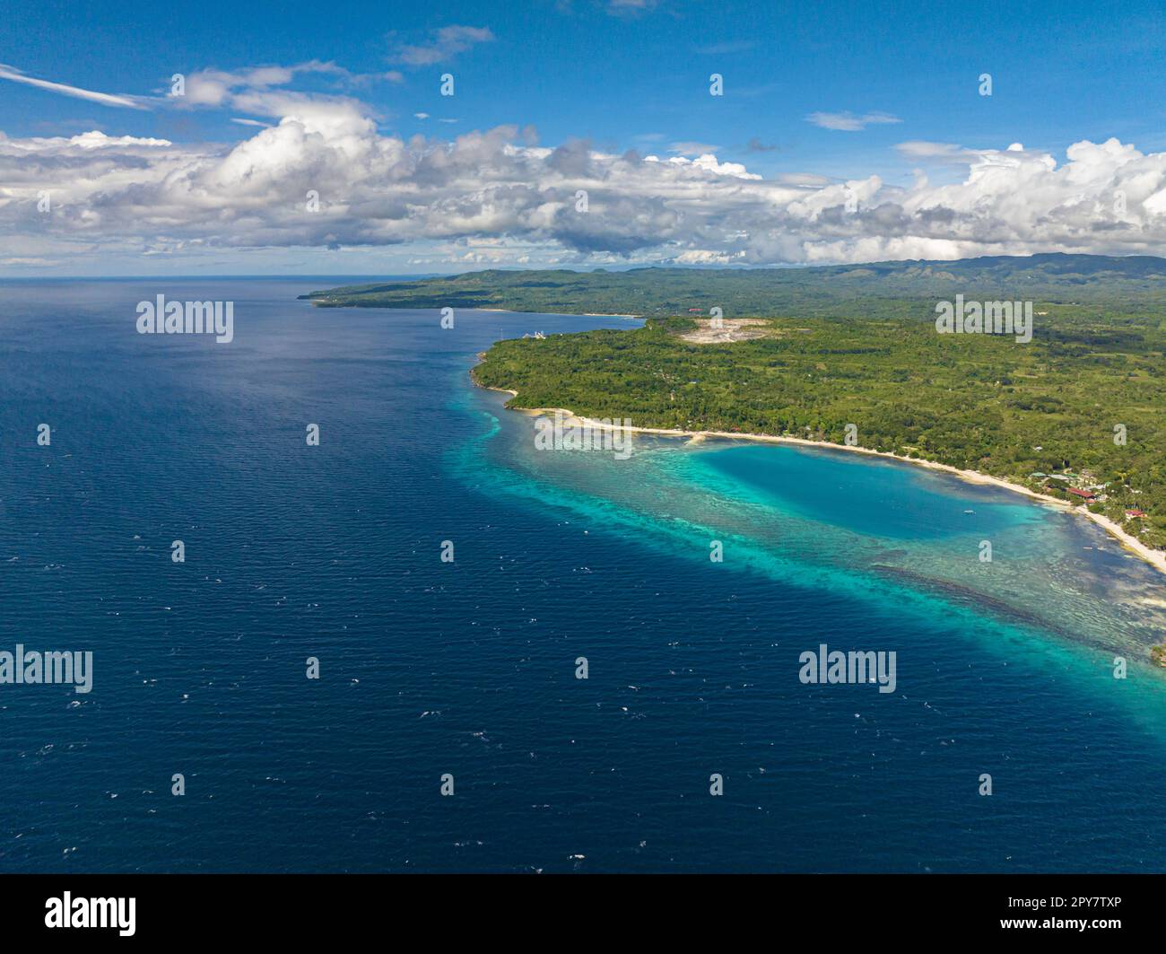 A body of land surrounded by Beautiful waves in outstanding blue ocean with a long white sandy beach. Siquijor, Philippines. Stock Photo