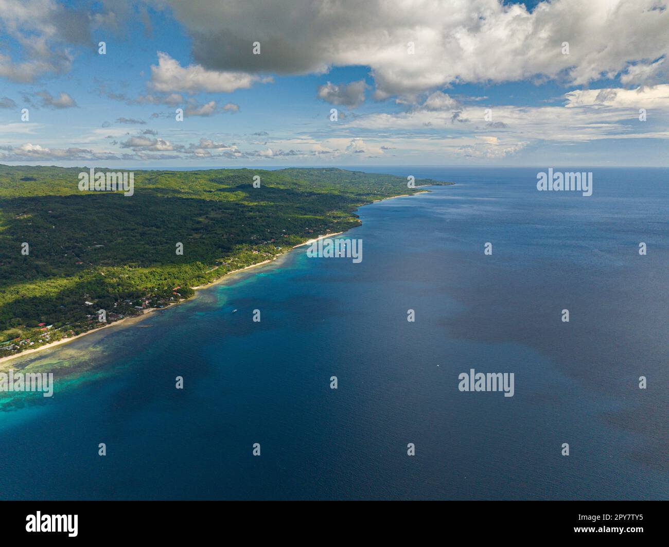 Aerial view of four boats enjoying the tropical island with a beach in the open ocean under the big clouds in the skyline. Siquijor, Philippines. Stock Photo