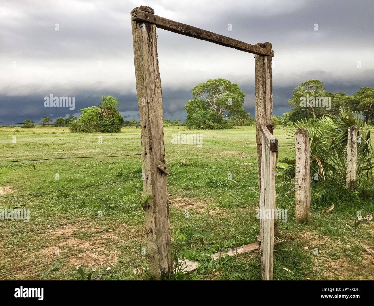 View through a wooden fence gate to typical pasture land with cloudy