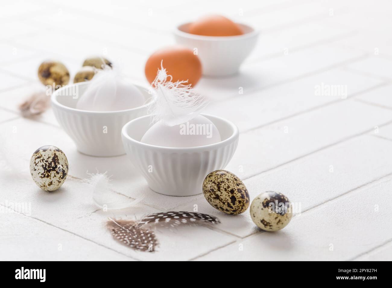Different eggs with feathers for Easter on white background Stock Photo