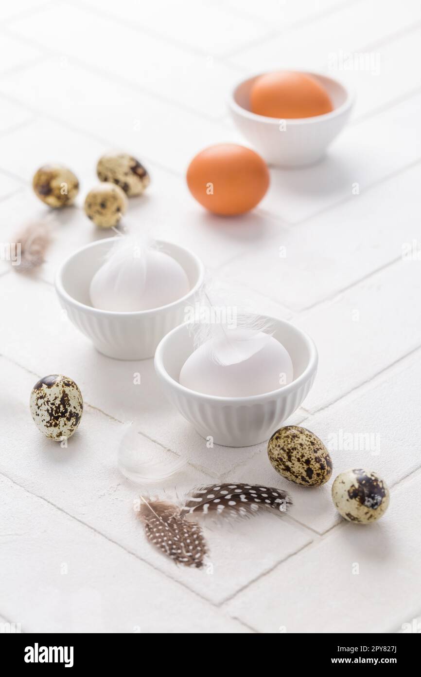 Different eggs with feathers for Easter on white background Stock Photo