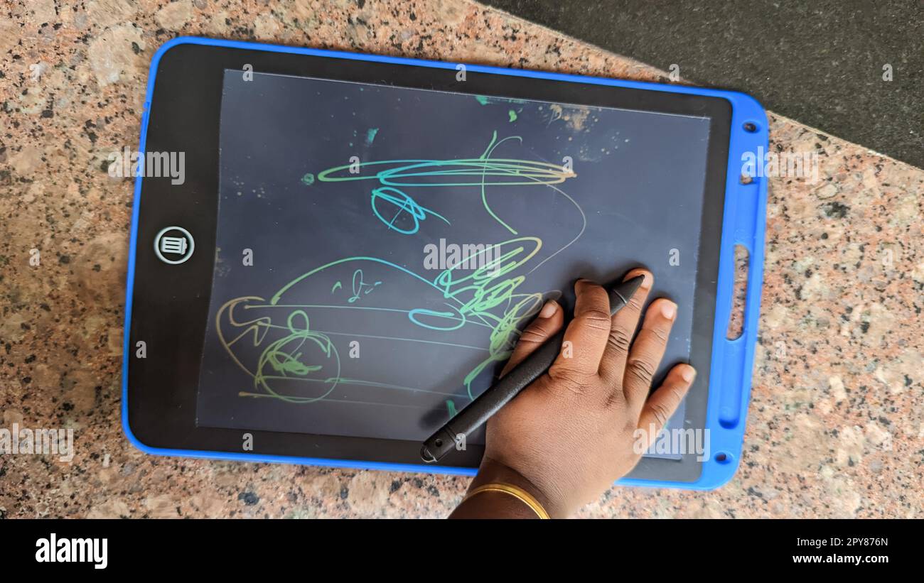 an infant child drawing random things and sketching in a colorful drawing tablet Stock Photo