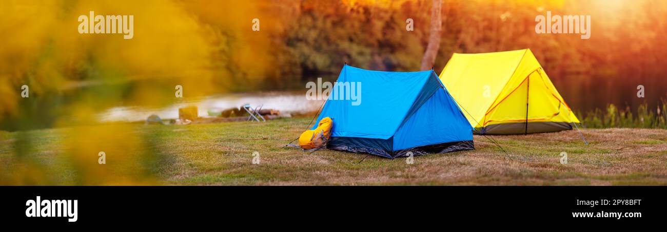 Panoramic view of the campground with colourful tents near the lake in wilderness park. Stock Photo