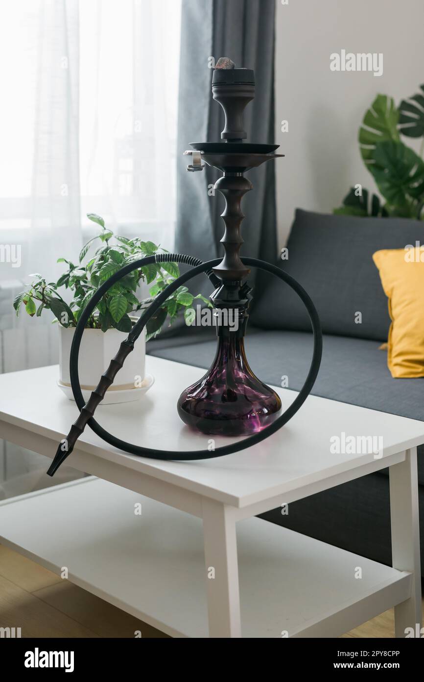 Hookah shisha with glass flask and metal bowl in room background