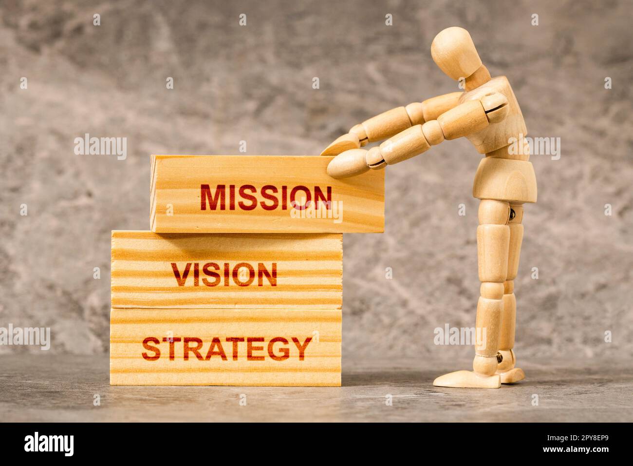 Wooden mannequin building up wooden blocks with  STRATEGY, VISION and MISSION text Stock Photo