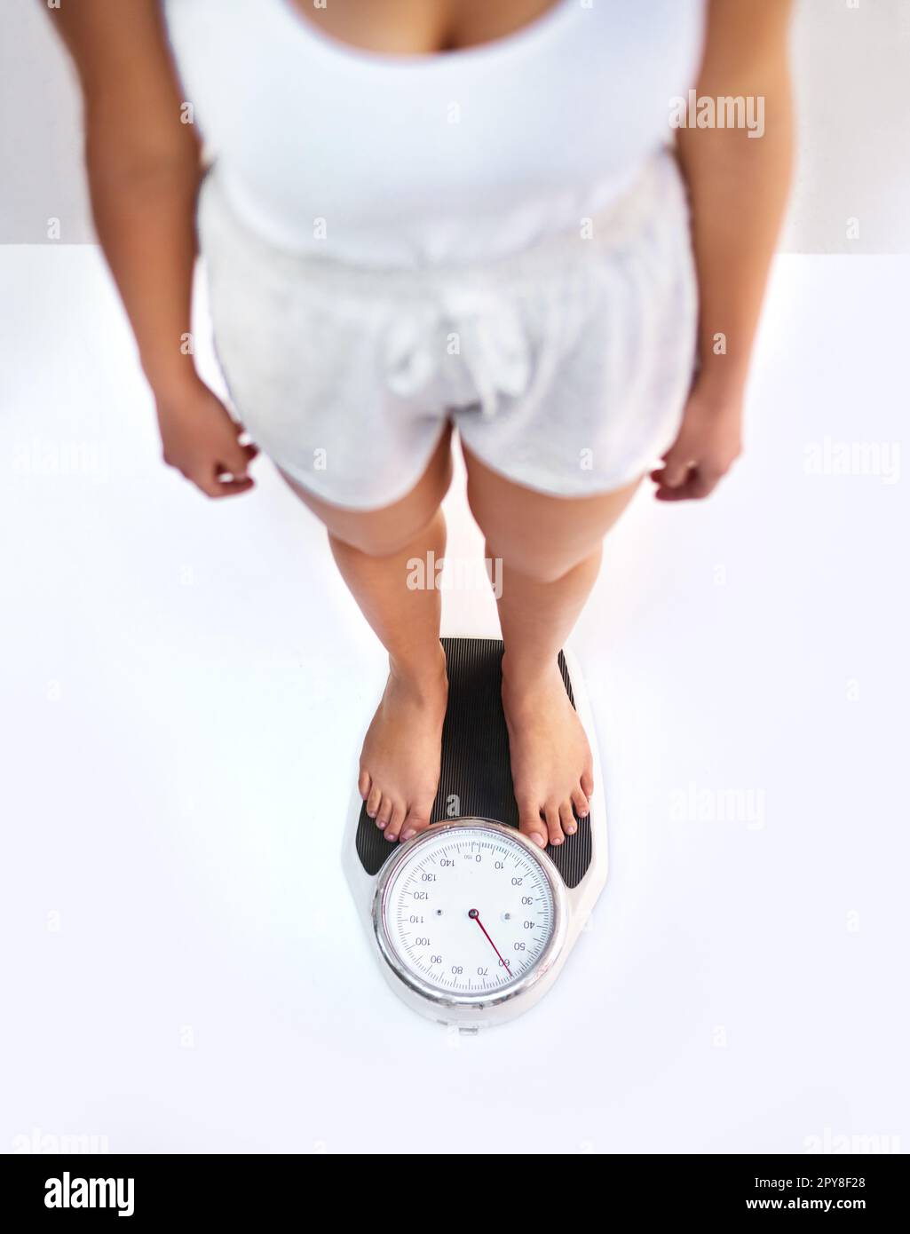 A woman standing on a weighing scale in white background with a lose weight  now note on its display Stock Photo - Alamy