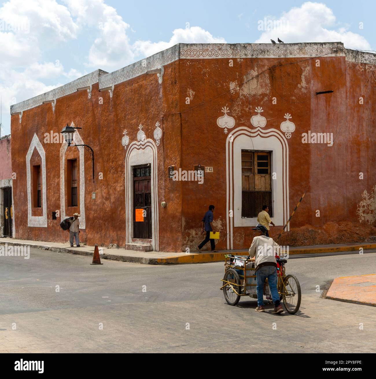 man pushing his tricycle along street past off Spanish colonial buildings, Vallodolid, Yucatan, Mexico Stock Photo