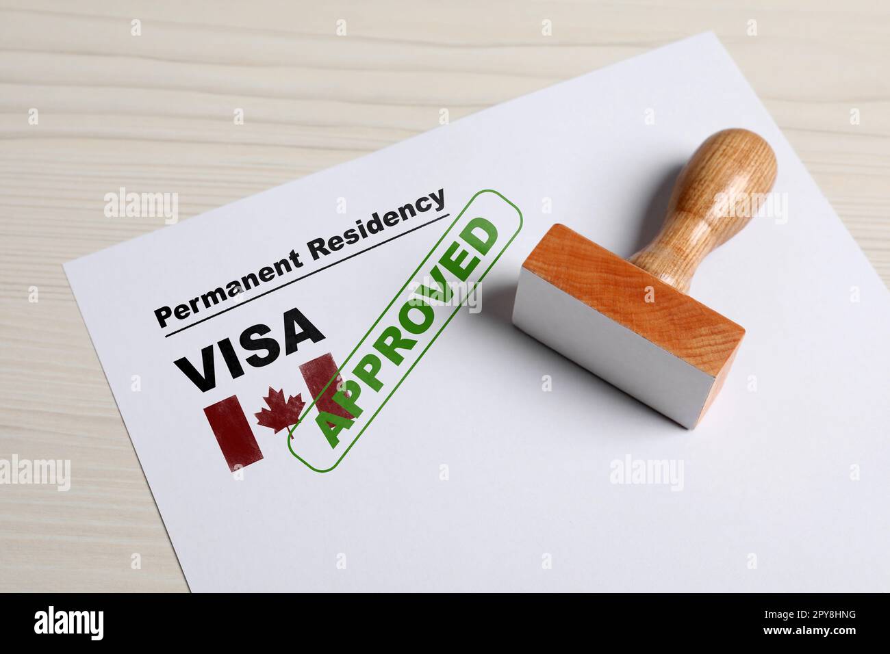 Document with approved permanent residency visa in Canada and stamp on white wooden table Stock Photo