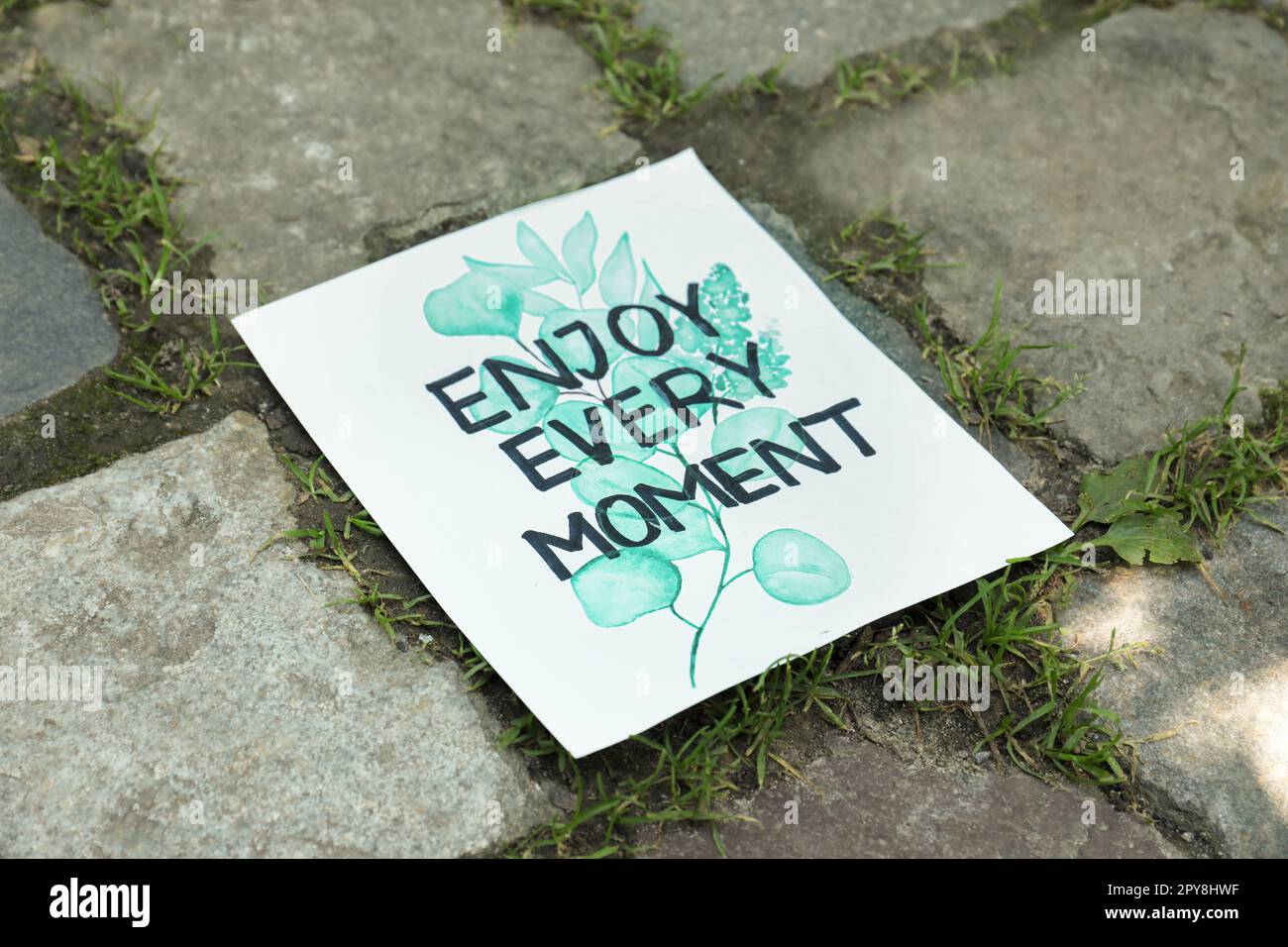 Card with phrase Enjoy Every Moment on ground Stock Photo