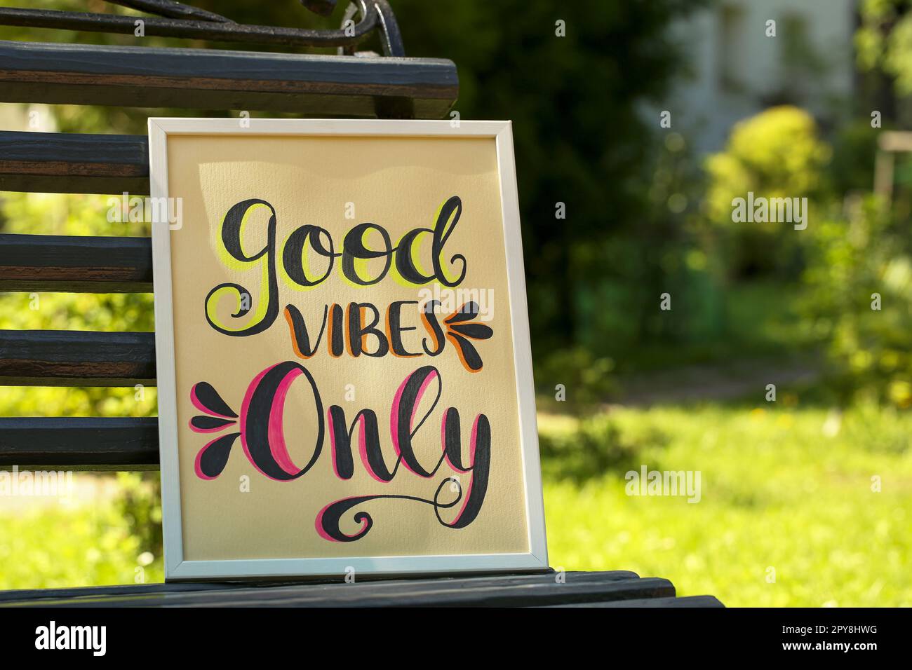 Poster with phrase Good Vibes Only on black wooden bench outdoors Stock Photo