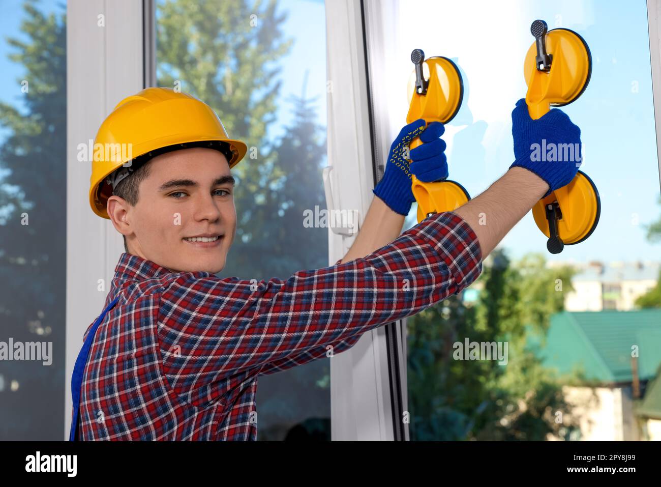 Worker using suction lifters during plastic window installation indoors Stock Photo