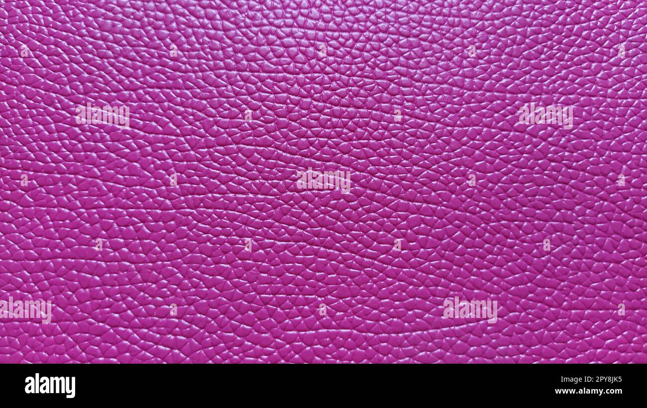 Artificial leather is bright pink or fuchsia. Distinct furrows and elevations on the surface of a bag or shoe. Reflection of the light. Fashion accessory made of imitation pig skin. Close-up Stock Photo