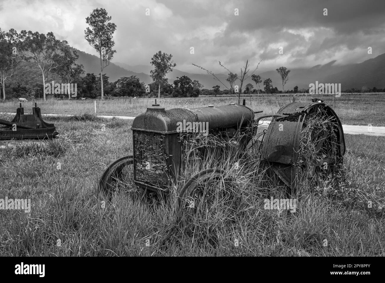 A rusting vintage tractor beside the Murray Falls Road, Murray Upper, Queensland, Australia Stock Photo