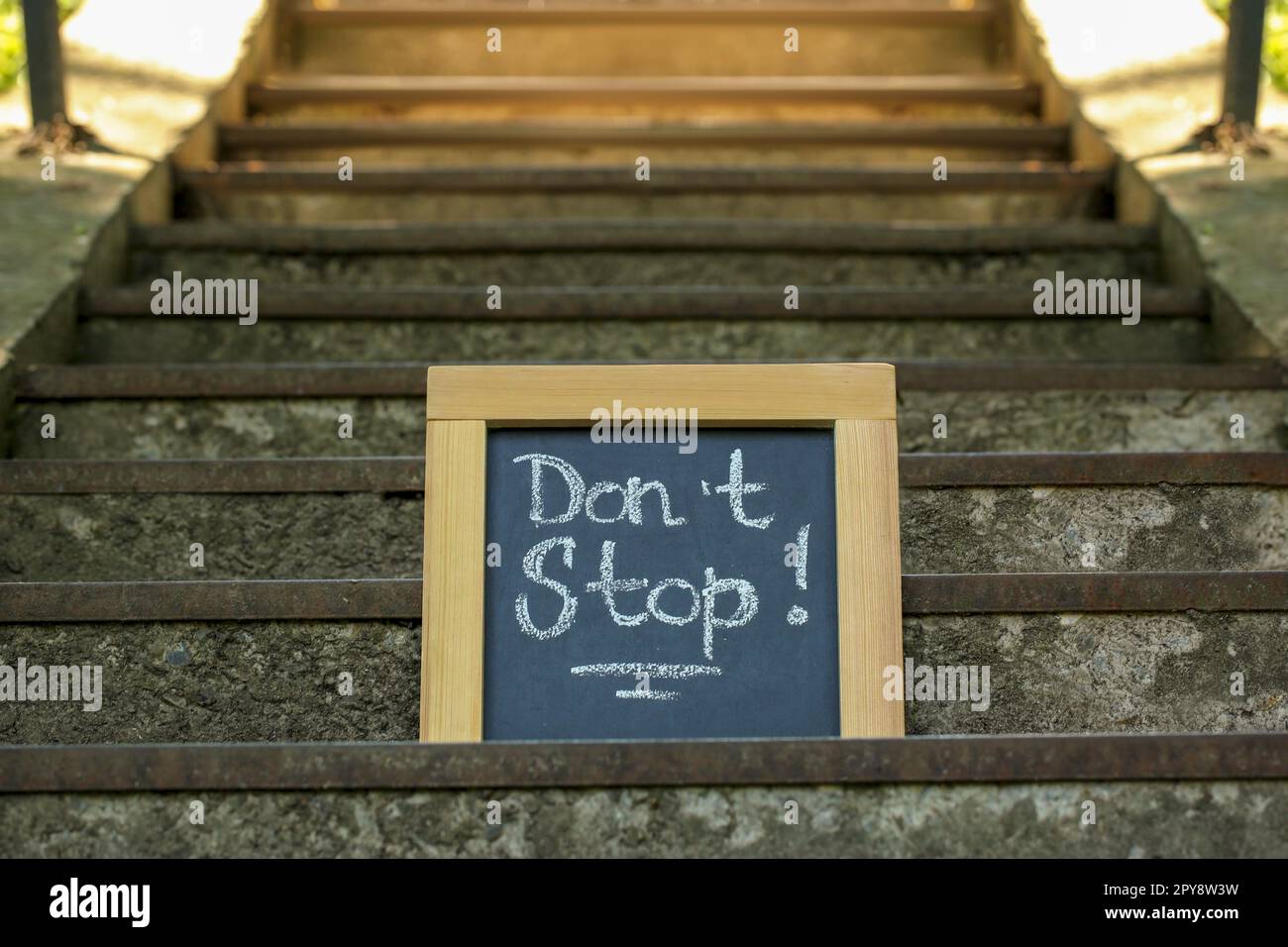 Chalkboard with phrase Don't Stop on stone stairs outdoors Stock Photo