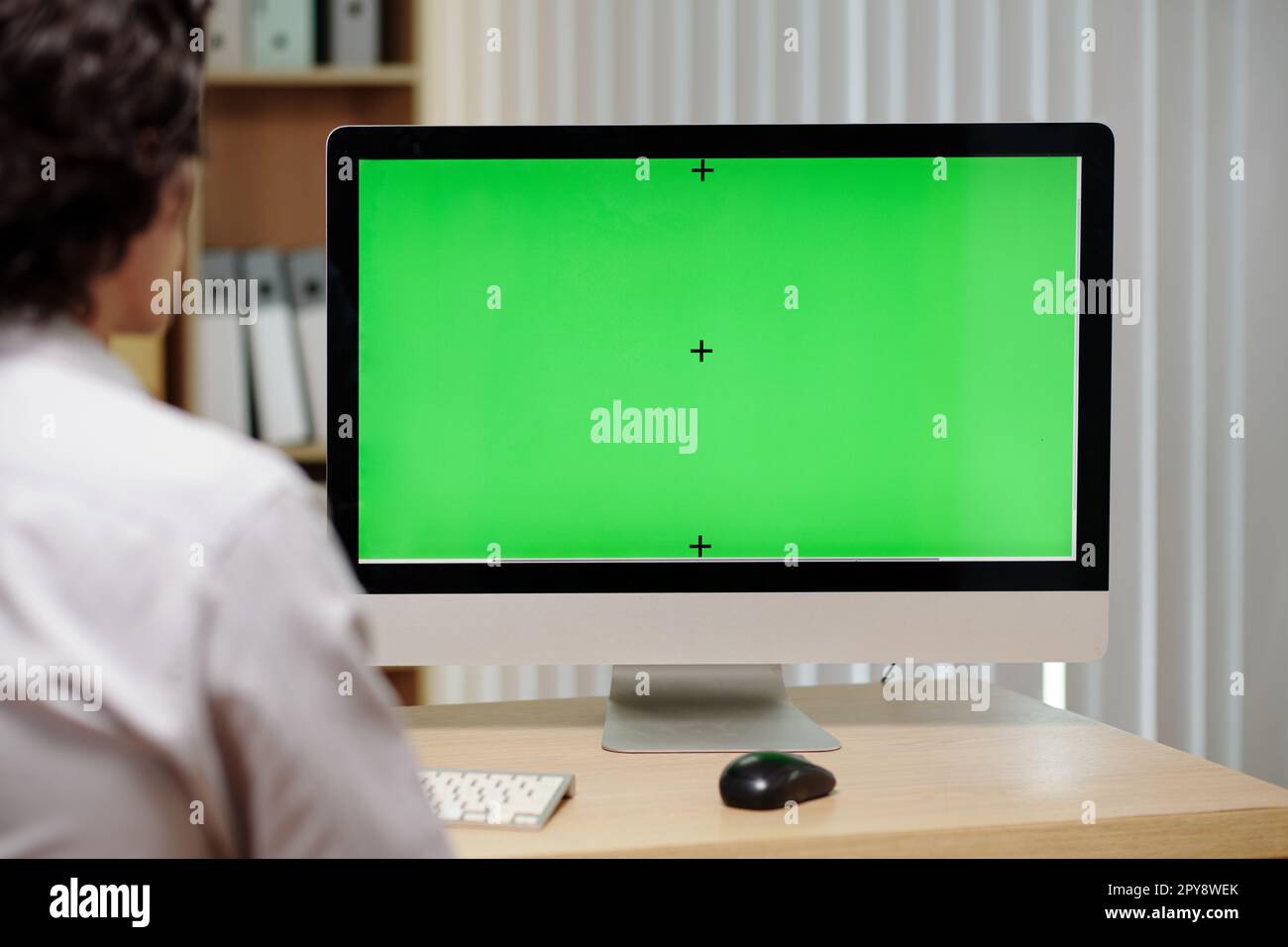 Computer screen with green screen on desk in front of businessman Stock Photo
