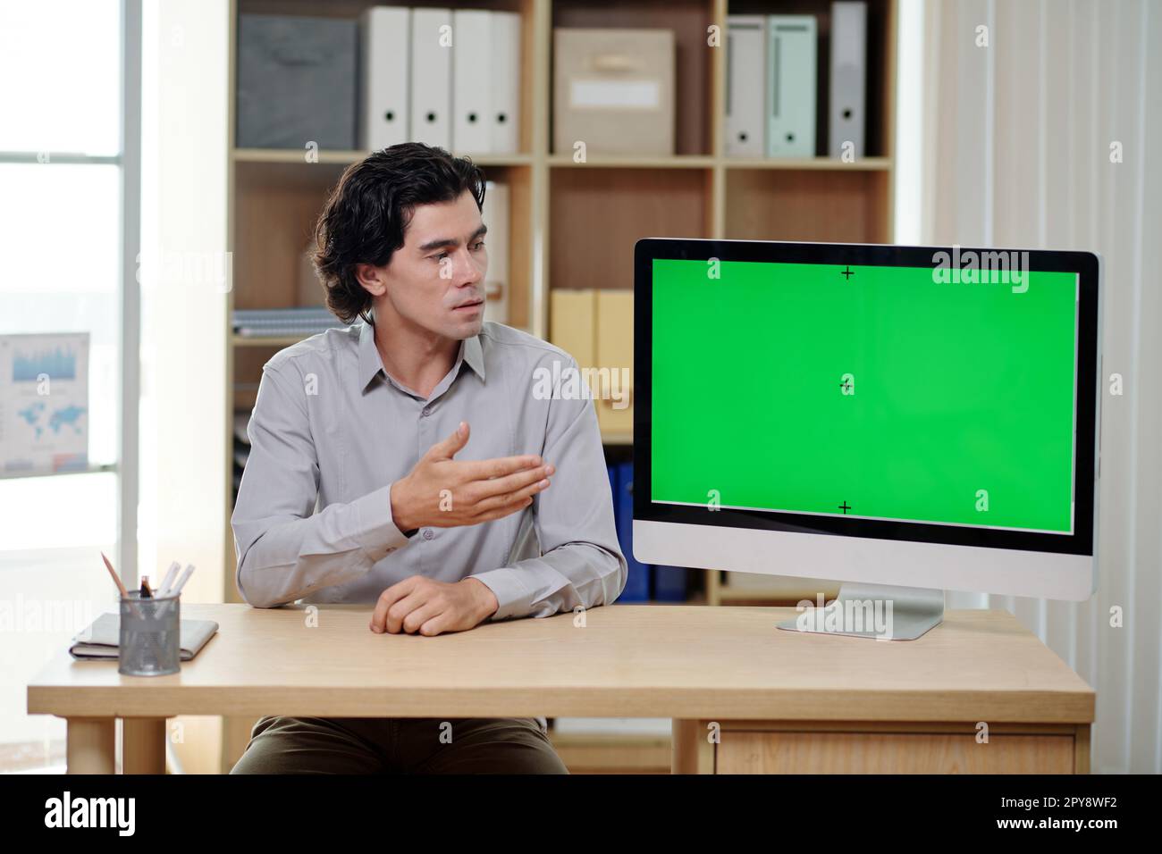 Serious businessman showing presentation on computer screen in meeting with investors Stock Photo