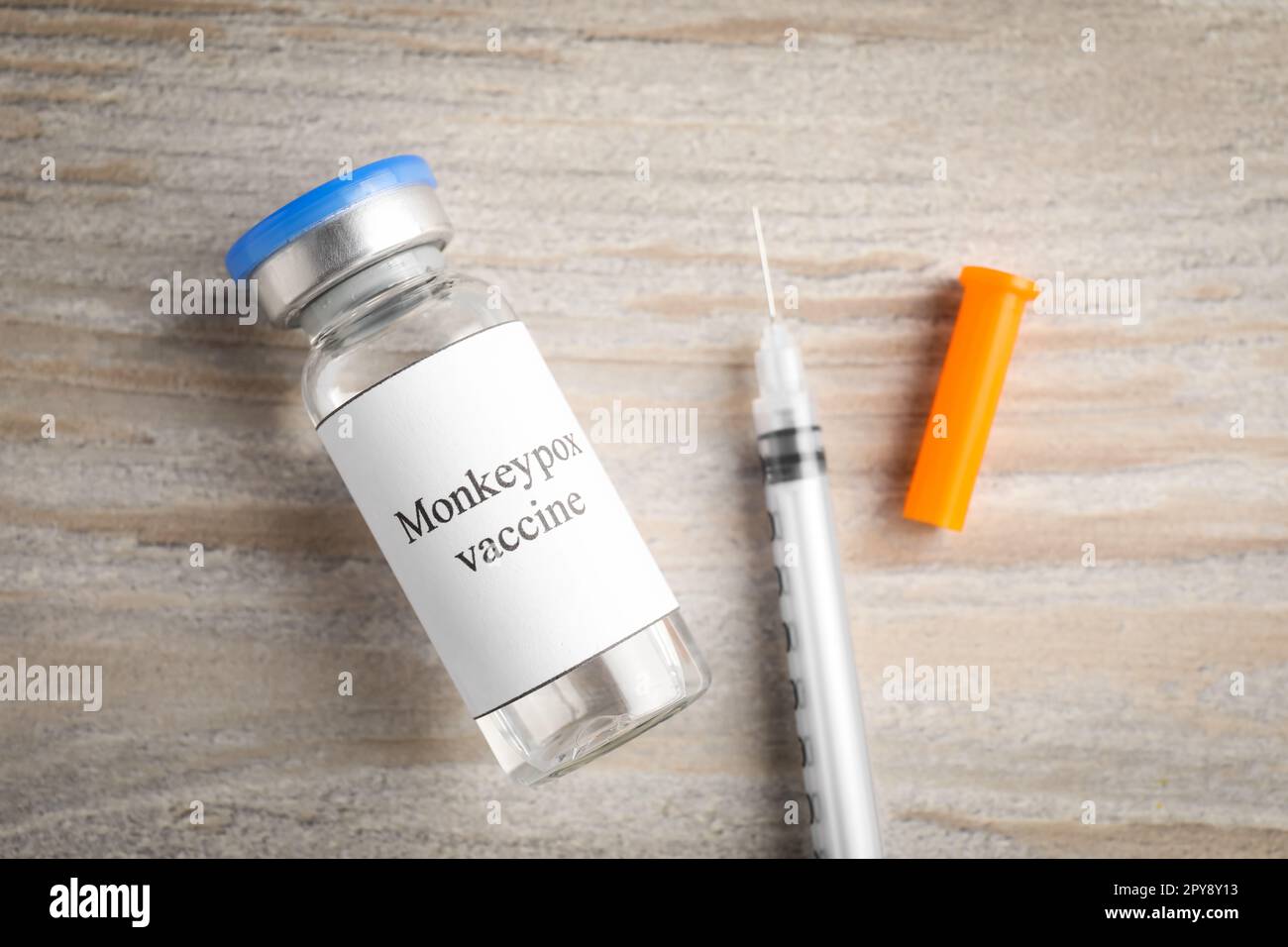 Monkeypox vaccine in glass vial and syringe on wooden table, flat lay ...