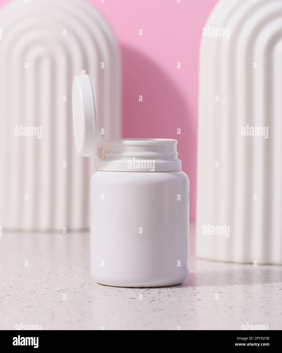 White plastic jar with an open lid for cosmetics and medical preparations on a pink background Stock Photo