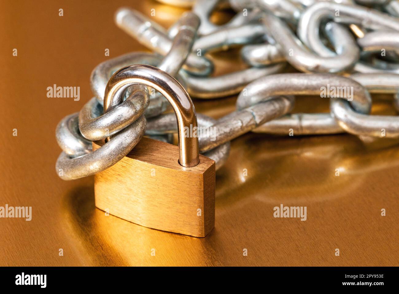 Yellow padlock with a pile of metal chain Stock Photo